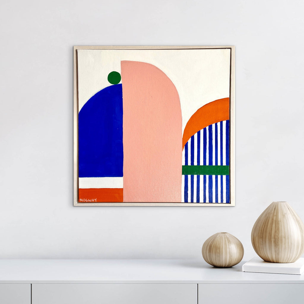 Abstract art print with geometric shapes on a white wall above a shelf.