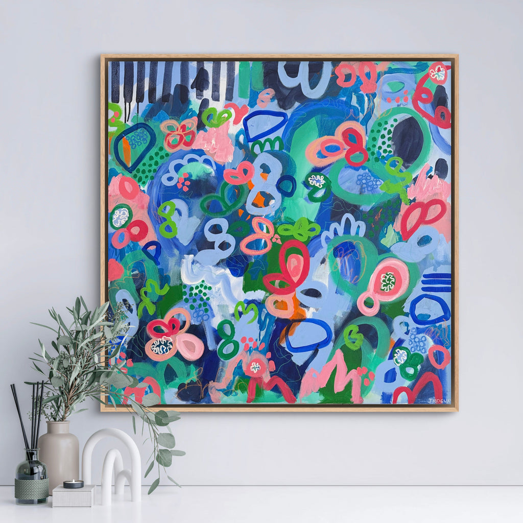 Colorful abstract art piece in a wooden frame on a white wall.